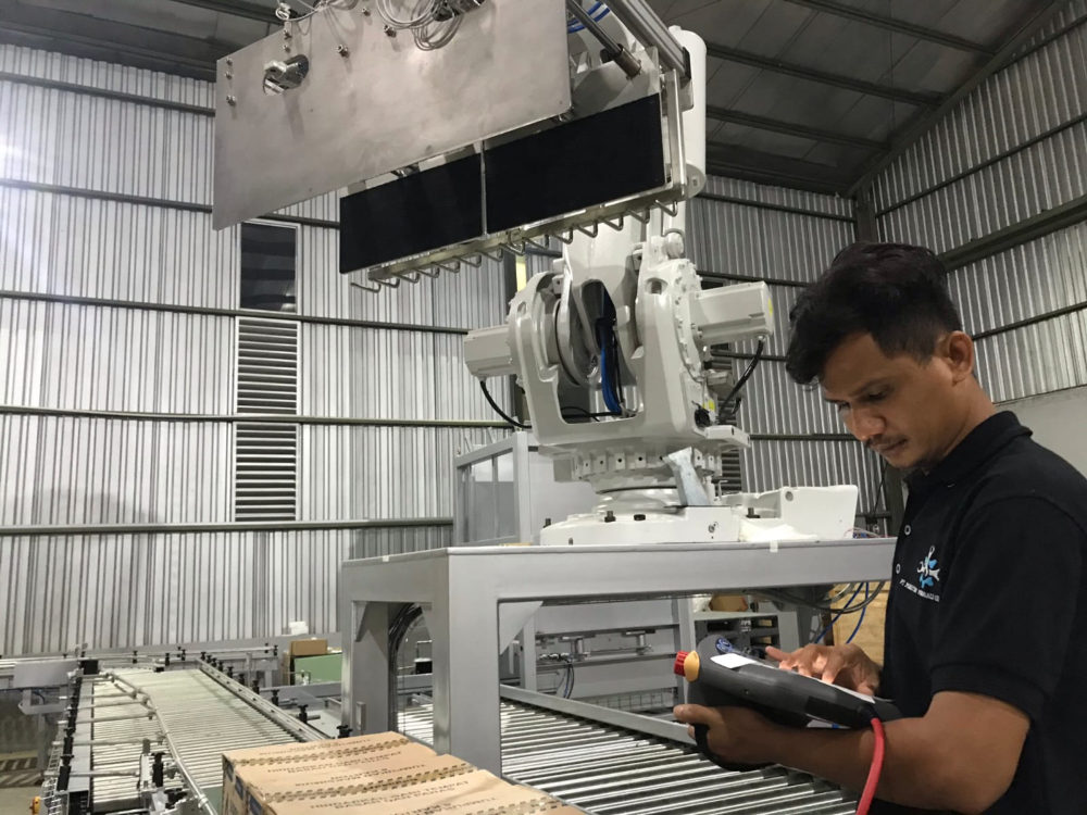 Teknisi MMG memprogram robot palletizing menggunakan teach pendant